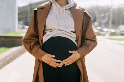 Mulher grávida em ambiente urbano, com as mãos sobre a barriga.