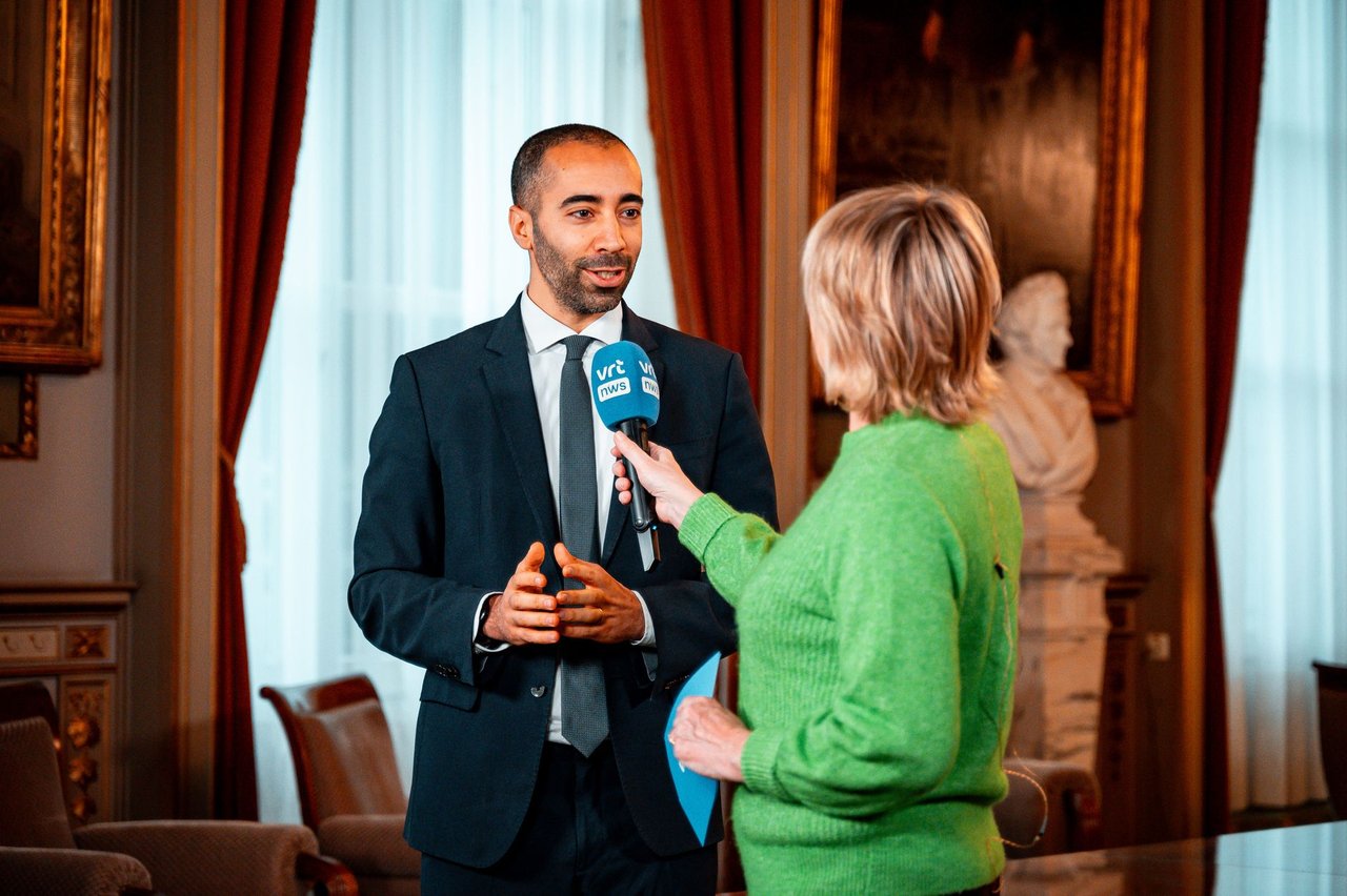 Jornalista entrevista um profissional em um ambiente formal.