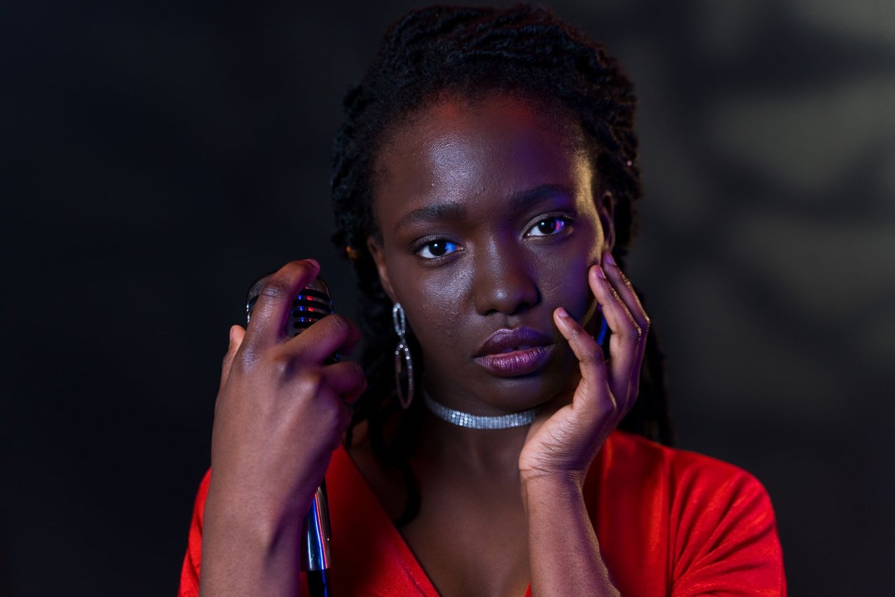 Mulher segura um microfone e posa em um retrato com expressão confiante.